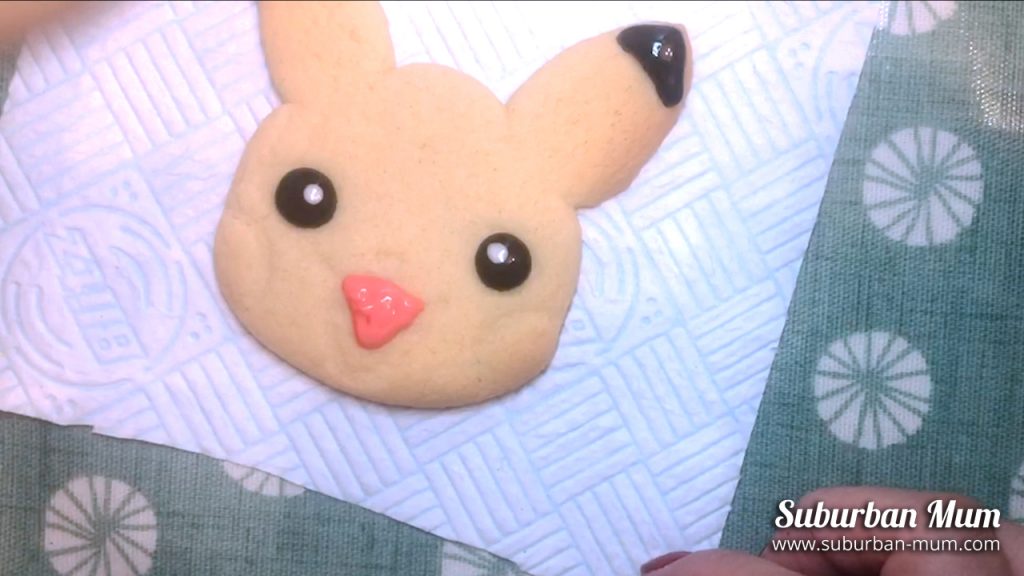 using pink icing to ice the tongue on the pikachu cookie