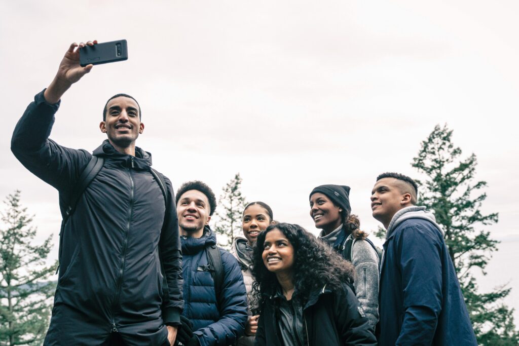 a group of teens with different ethnicities wearing black coats taking a selfie