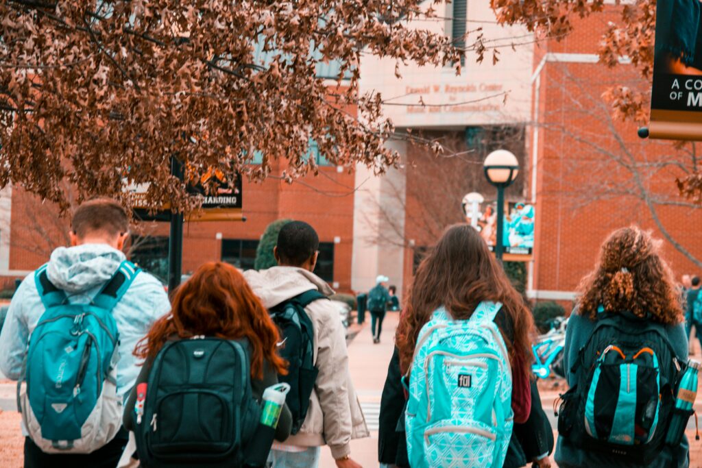 hree students walking with backpacks along a school pathway