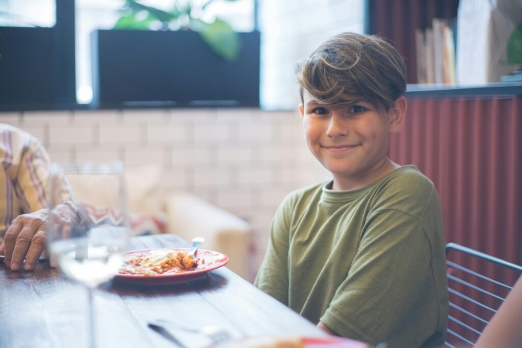 Smiling boy sitting at dinner table enjoying a meal — kids eat free October half term 2025