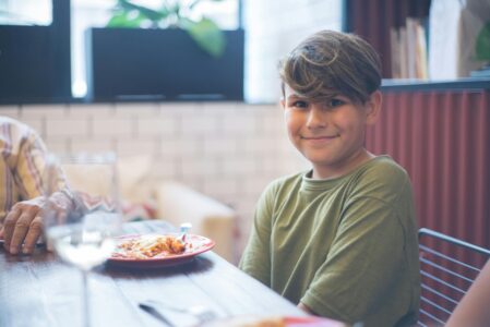 Smiling boy sitting at dinner table enjoying a meal — kids eat free October half term 2025