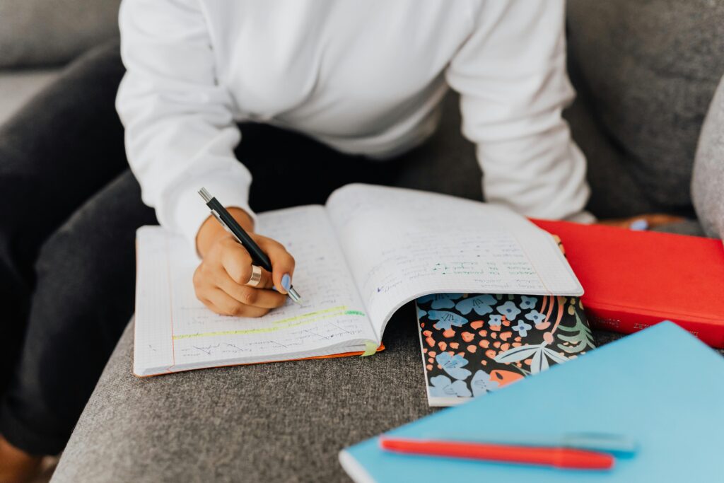 pexels-karola-g-5311619 Student concentrating on their assignment, jotting down ideas in a notebook during revision