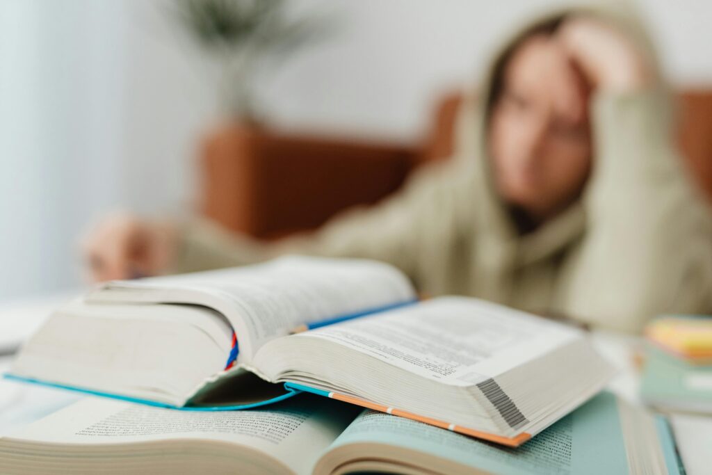 pexels-karola-g-6958551 A tired student’s desk with open textbooks and scattered papers, capturing the focus and fatigue of exam preparation
