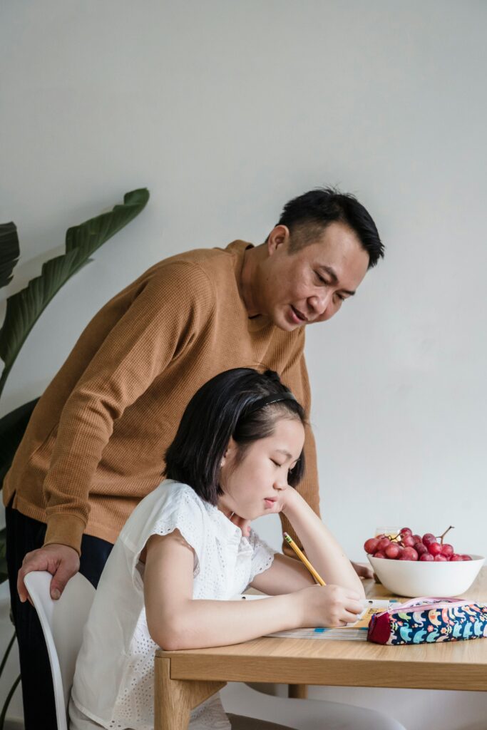 A young girl sitting at a table looking thoughtful, suggesting reflection and emotional awareness.