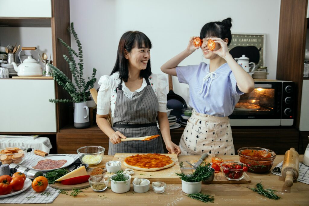https://www.pexels.com/photo/positive-women-having-fun-cooking-pizza-5907819/