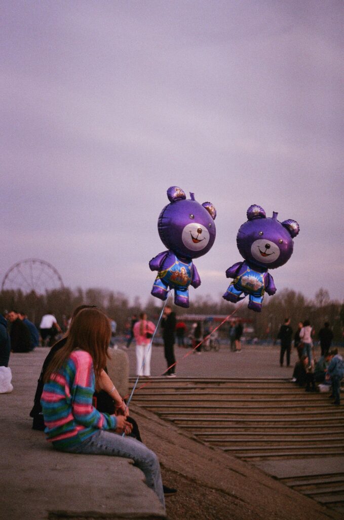 Someone seated in a park with colourful balloons"
