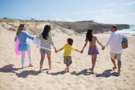 Family holding hands while walking on beach