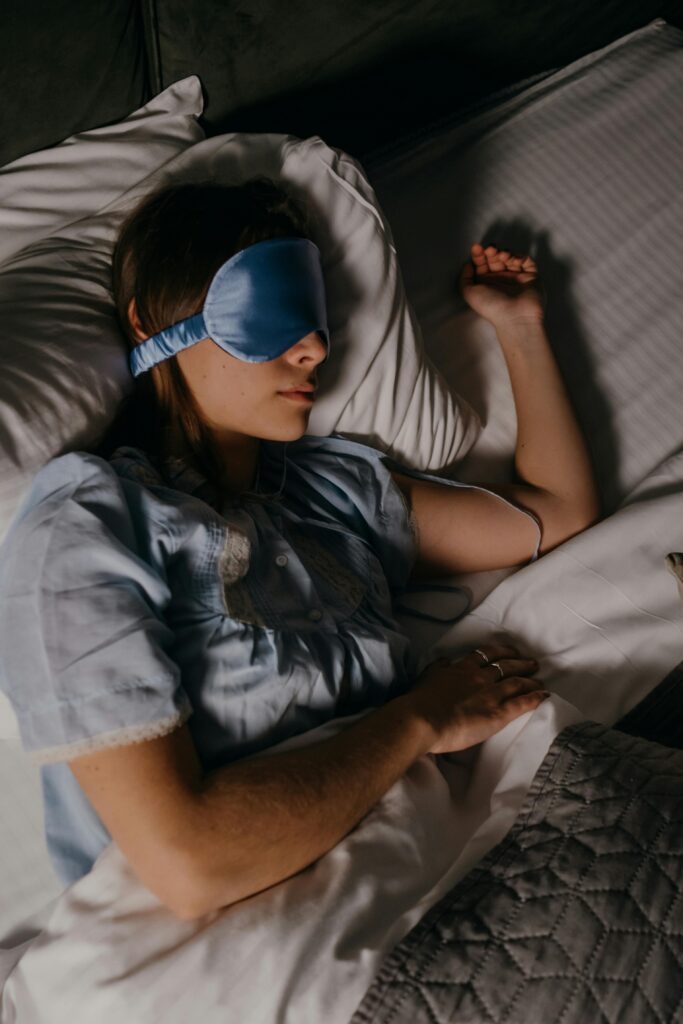pexels-polina-kovaleva-6541083 Woman sleeping in bed with a blue eye mask.