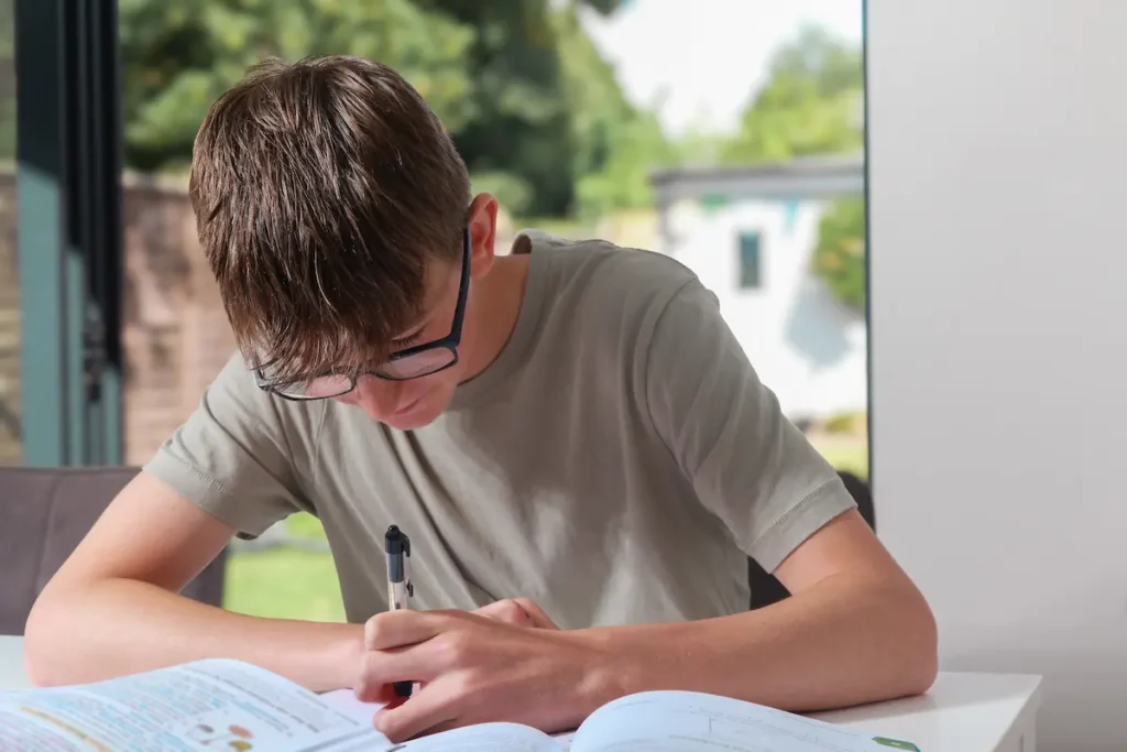 Teenager revising at home wearing glasses and studying notes