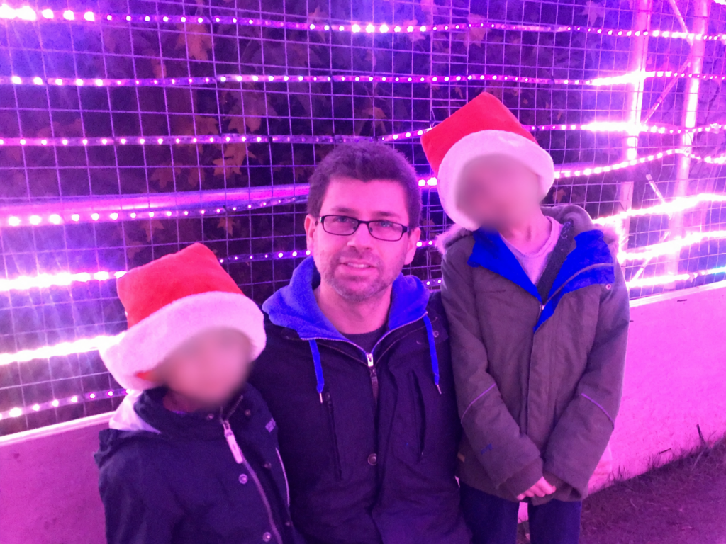 Family walking through the illuminated light tunnel at Christmas at Kew